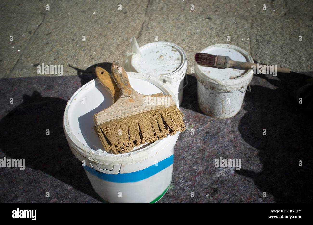 Painter brushes over buckets. Stone granite floor protected with blanket. Stock Photo