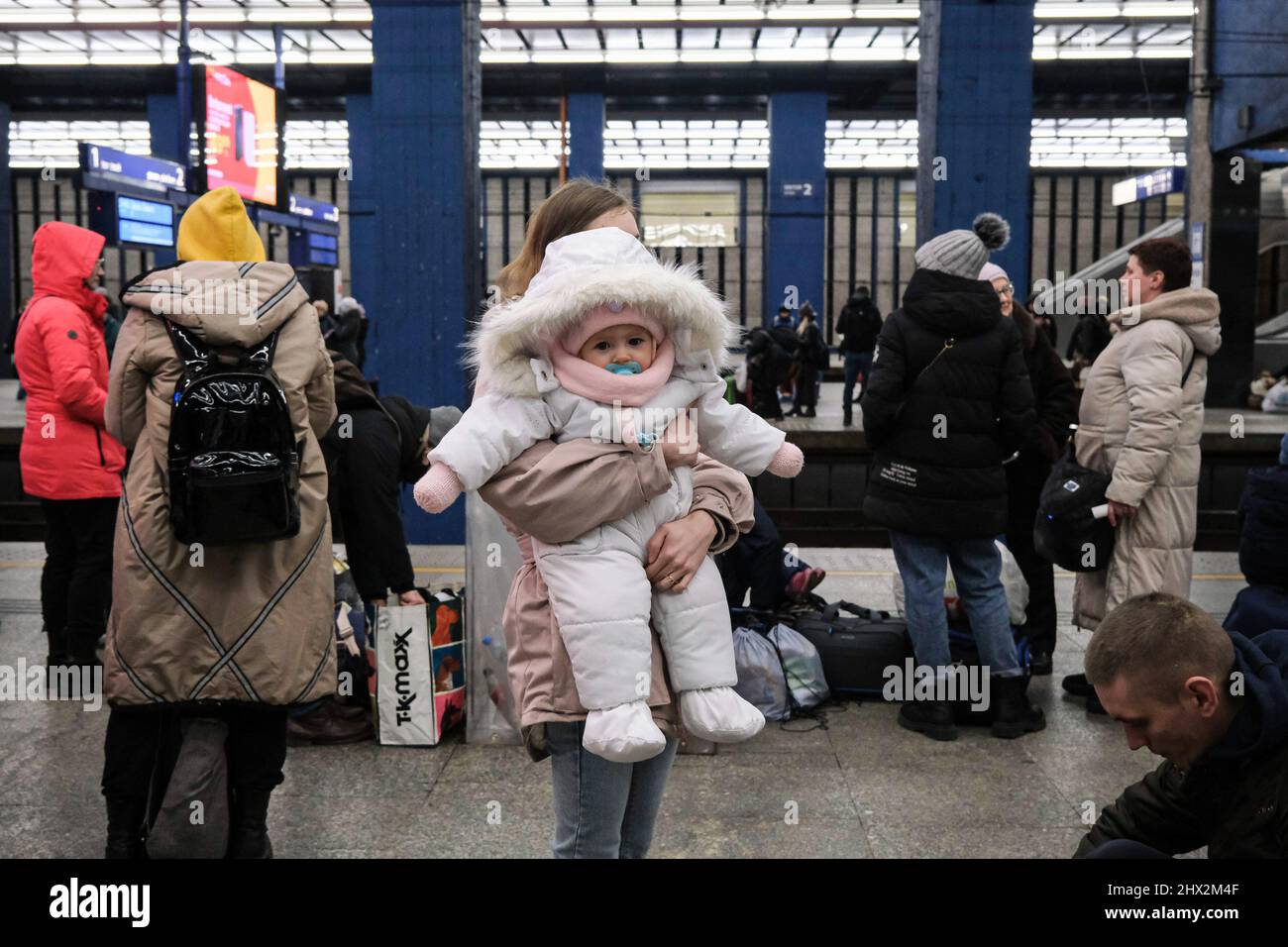 A woman carries her baby in her arms at the train platform of Warszawa Centralna Railway Station, as they wait for transit to other cities and countries for settling down. As war crisis in Ukraine continues, millions of Ukrainians have been fled from their homeland to Poland, most of them are women and children. Most of them temporarily resting in railway stations in Warsaw and awaiting for settling down. According to UN agency, the numbers of refugee migration have hit 1.5 million, which is the fastest-ever since the Second World War. The Polish government have announced a plan of 8 billion z Stock Photo