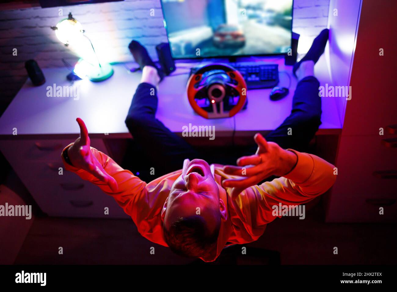 Male gamer playing racing games on the computer. He uses the steering ...