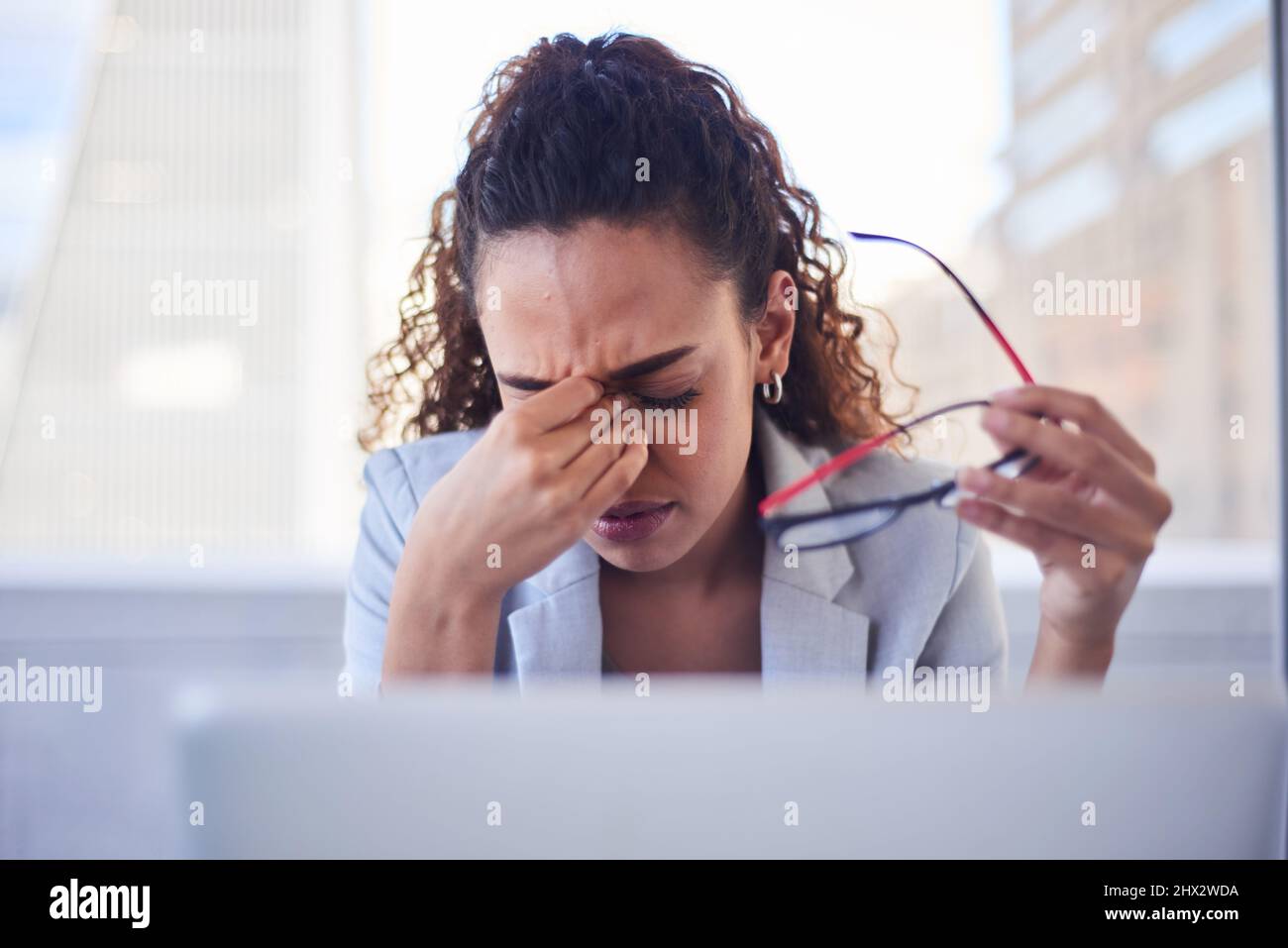 A young woman rubs her eyes and takes off her eyeglasses due to eye strain Stock Photo