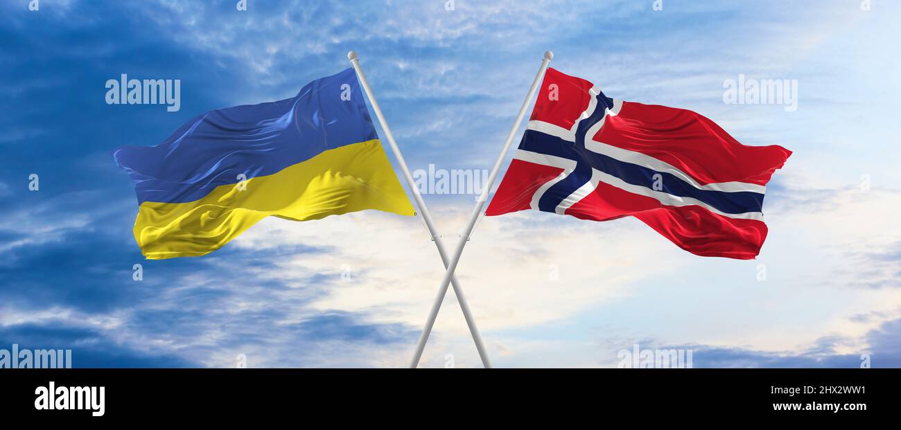 two crossed flags Norway and Ukraine waving in wind at cloudy sky ...