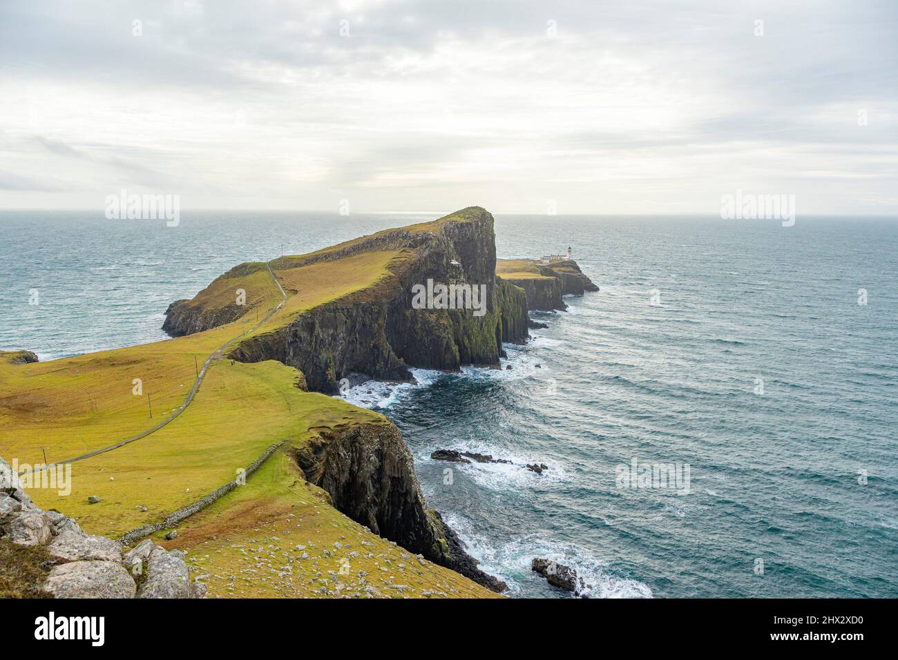 Neist Point Lighthouse, big cliff, cloudy day, sun rays, Skye Island, Highlands, Scotland. Stock Photo