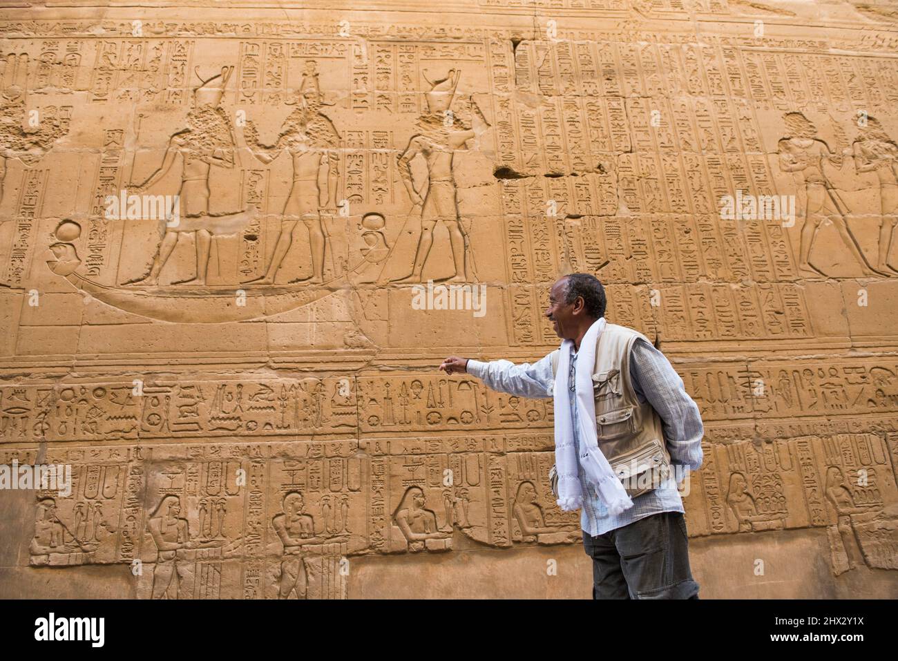 Mamdouh Kamel, Egyptian guide, deciphering the meaning of the painted engravings and hieroglyphs at the Temple of Edfu, Egypt, Northern Africa. Stock Photo