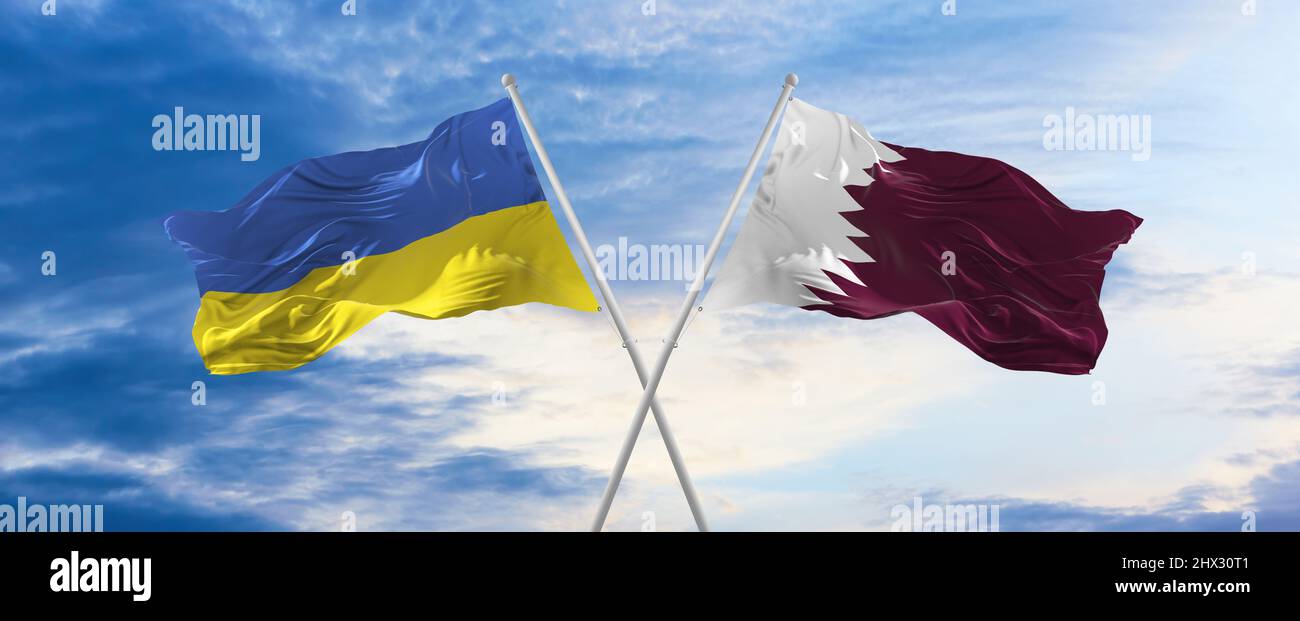 two crossed flags Qatar and Ukraine waving in wind at cloudy sky ...