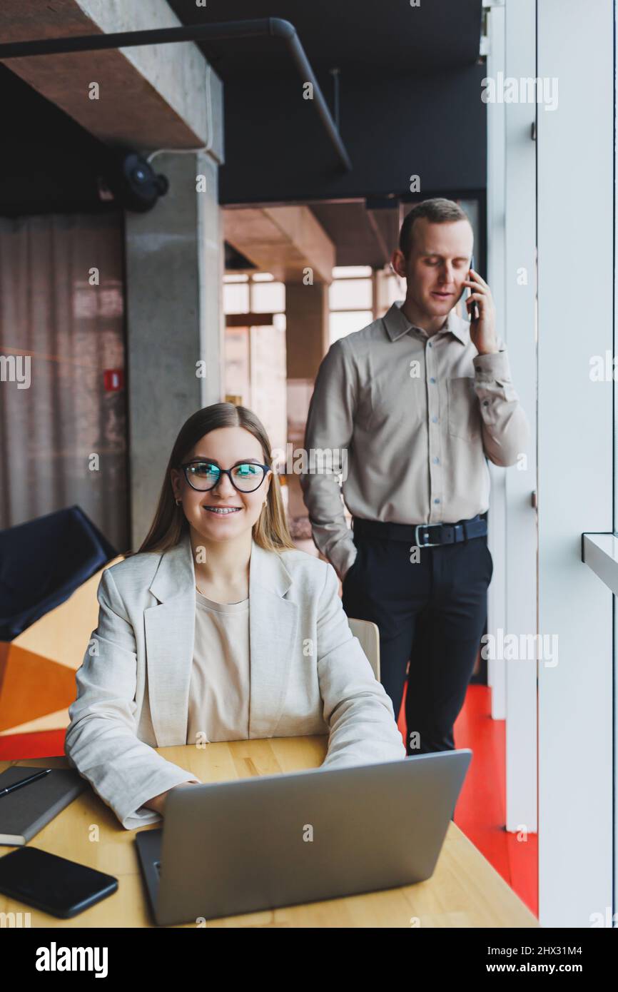 Cheerful female manager in a jacket doing office work and a smiling ...