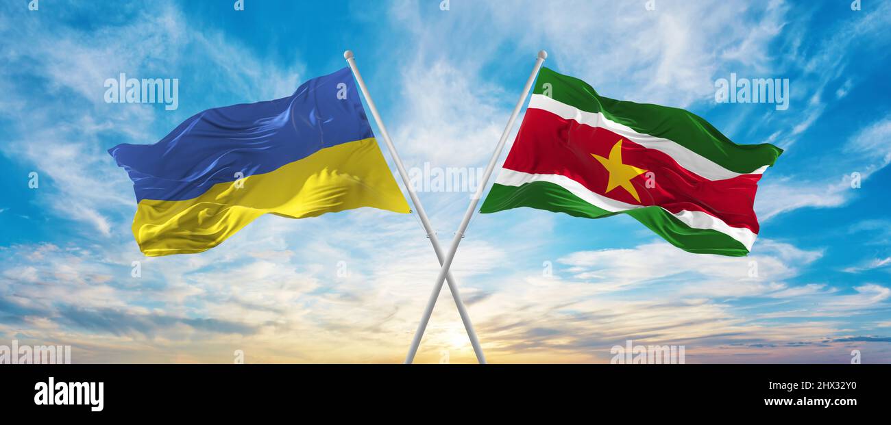crossed national flags of Ukraine and Suriname flag waving in wind at ...