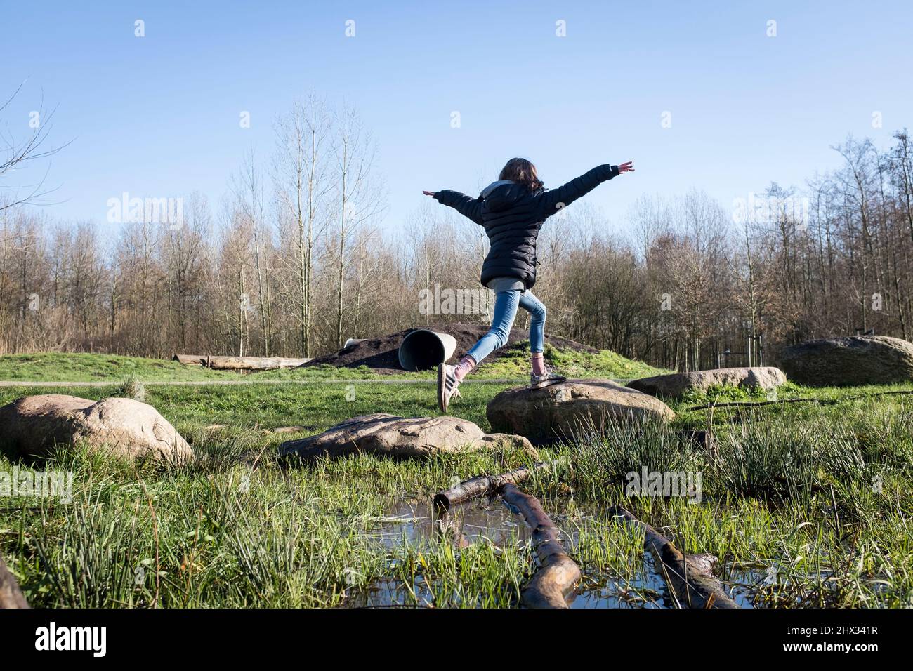 A young girl walks on stepping stones on an obstacle course in a park
