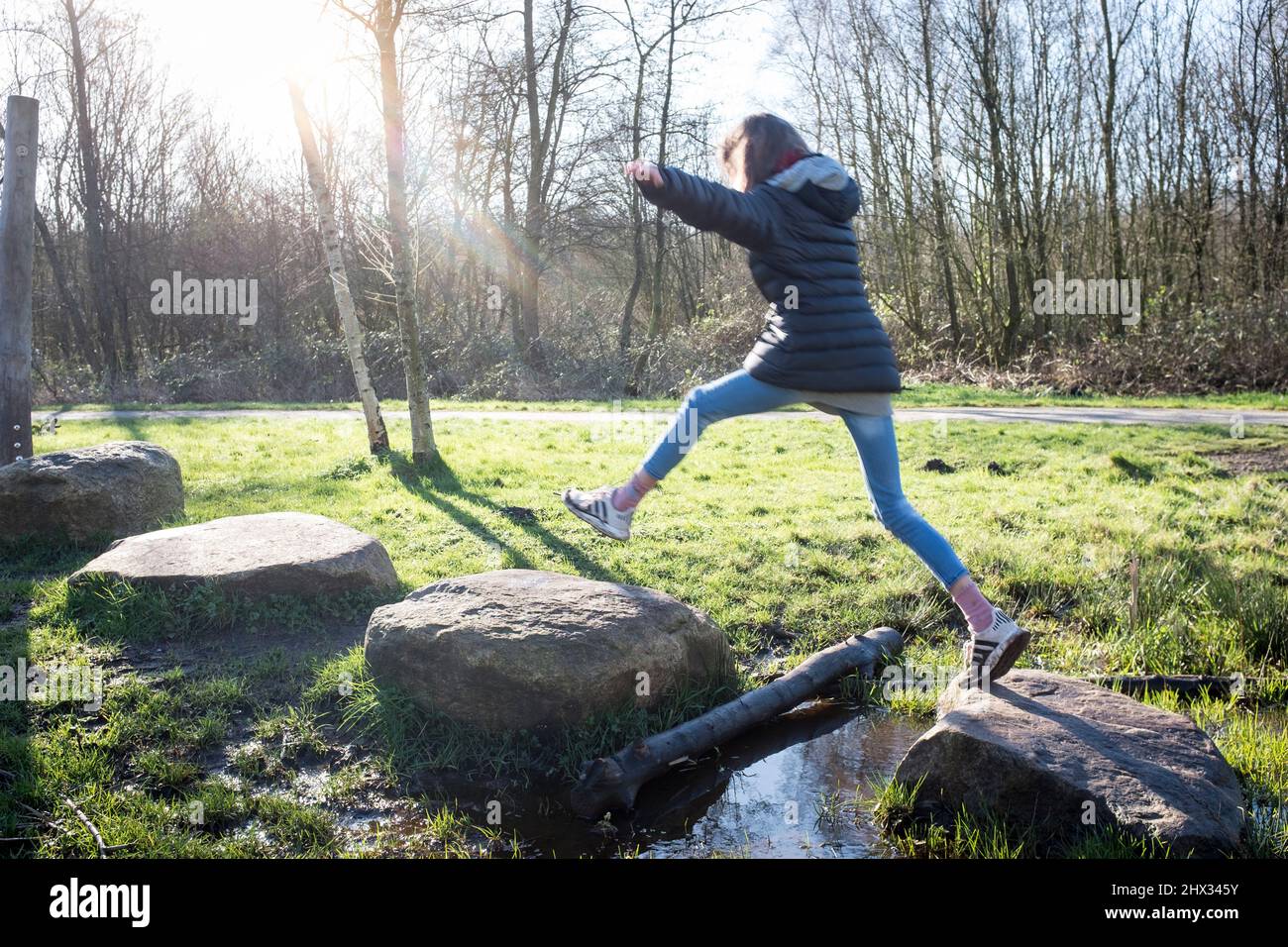 A young girl jumps between stepping stones on an obstacle course in a