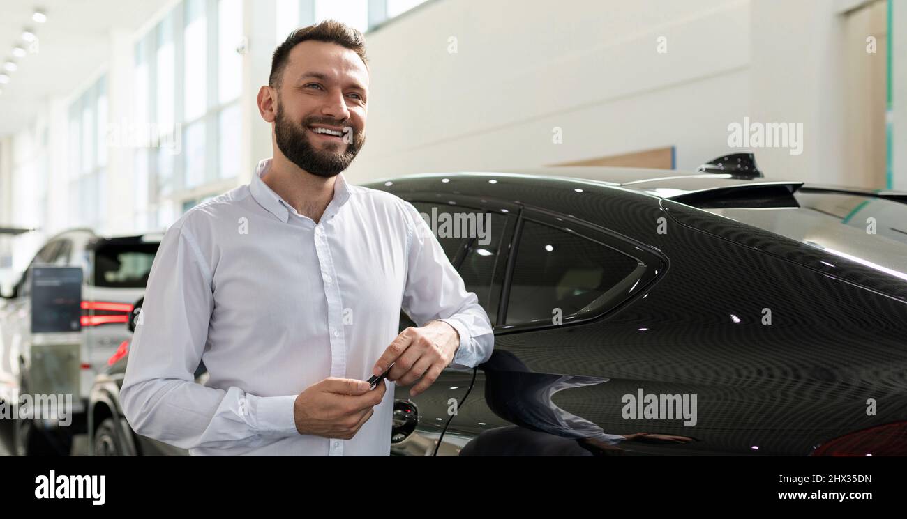 young businessman purchases a new car in a car dealership Stock Photo