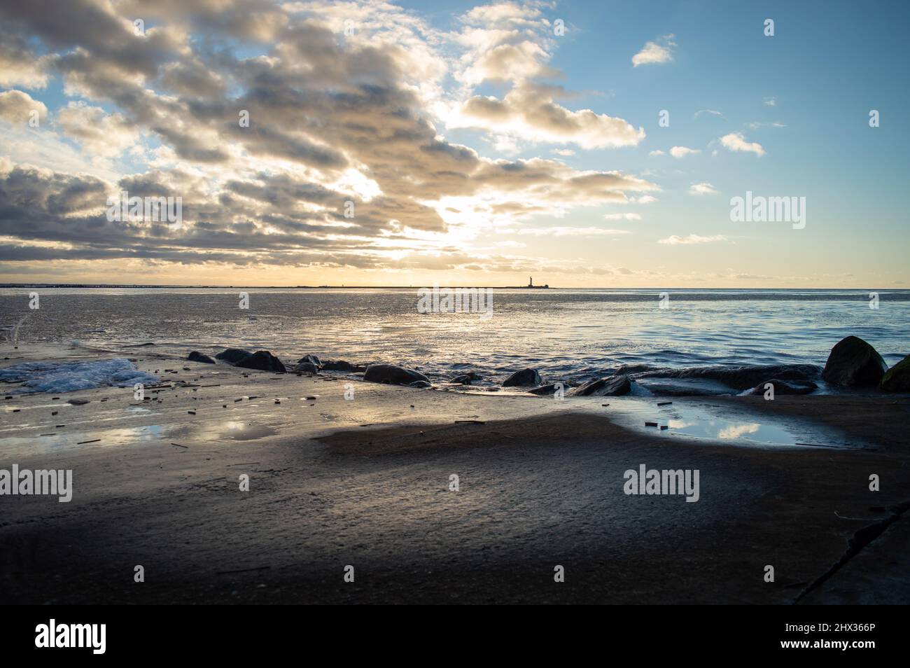 Sunset view from a pier. Cold climate mouth of the river at sunset. Distant lighthouse on horizon Stock Photo