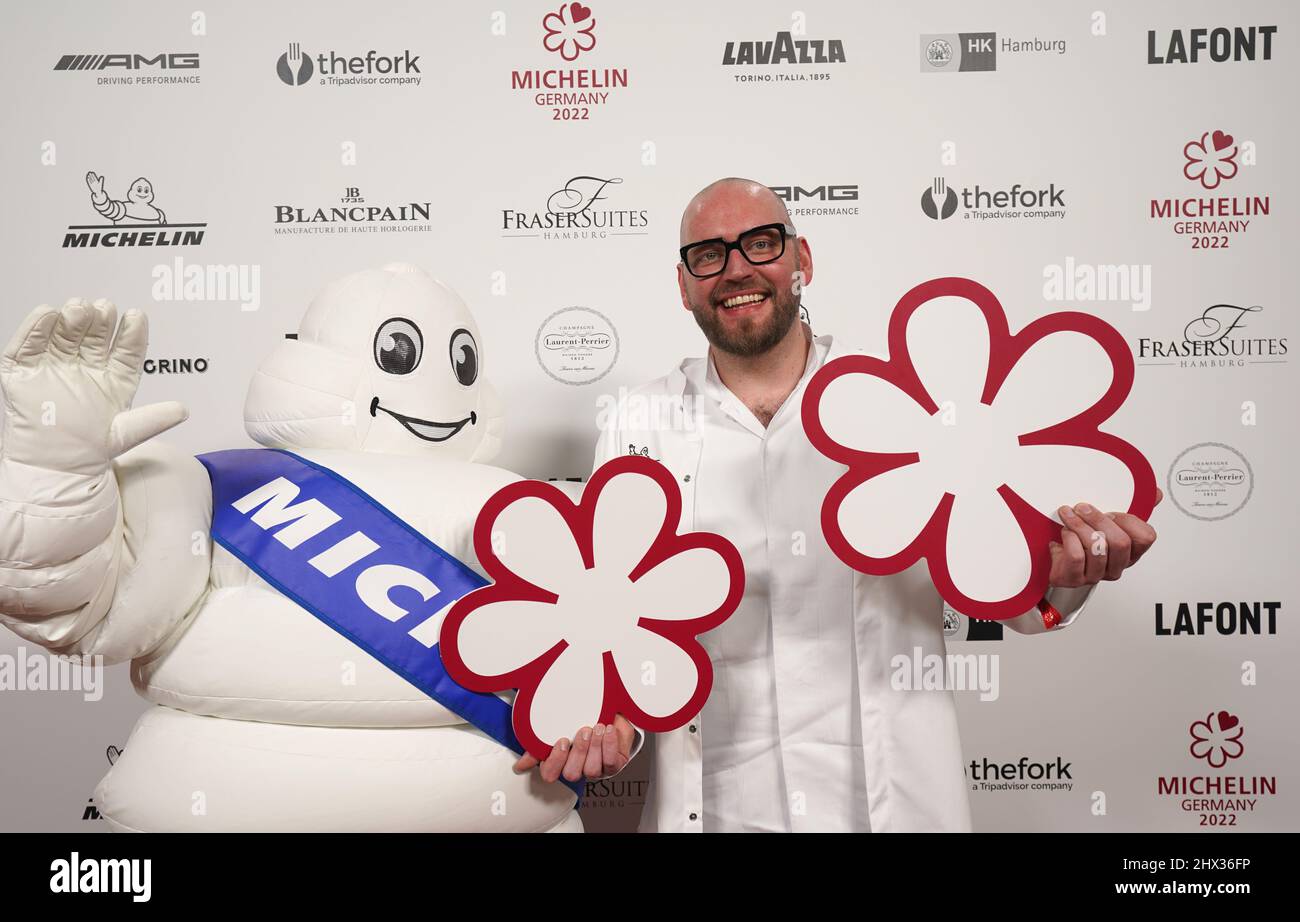 09 March 2022, Hamburg: Michelin-starred chef Thomas Imbusch of Hamburg's "100/200 Kitchen" restaurant symbolically holds up two stars at the Chamber of Commerce after the awarding of the 2022 Michelin stars for German restaurants. According to the director of the "Guide Michelin," the restaurant at the Elbbrücken has made intensive use of the Corona period to significantly improve its culinary offerings, Although the Corona pandemic has caused problems for many restaurateurs, the enforced breaks have spurred the country's top chefs to top performance. With new recipes and arrangements, chefs Stock Photo