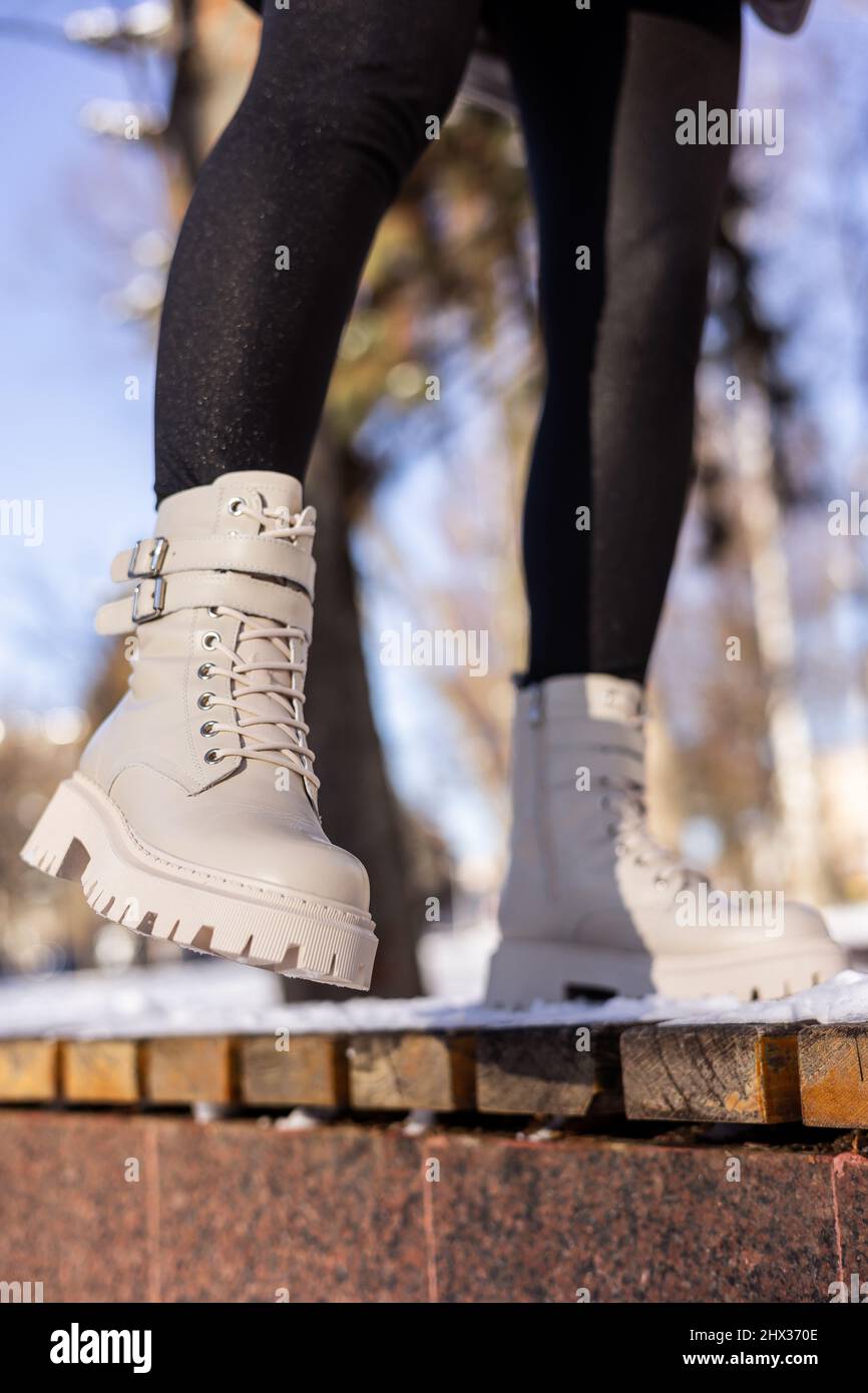 Woman in fashionable white boots on white snow, close-up. Women's legs in  stylish winter leather boots Stock Photo - Alamy