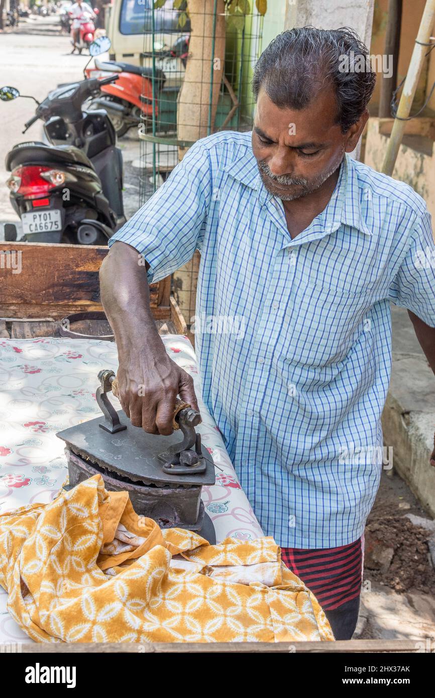 Presser pressing garments with a coal iron in a market stall, India Stock Photo