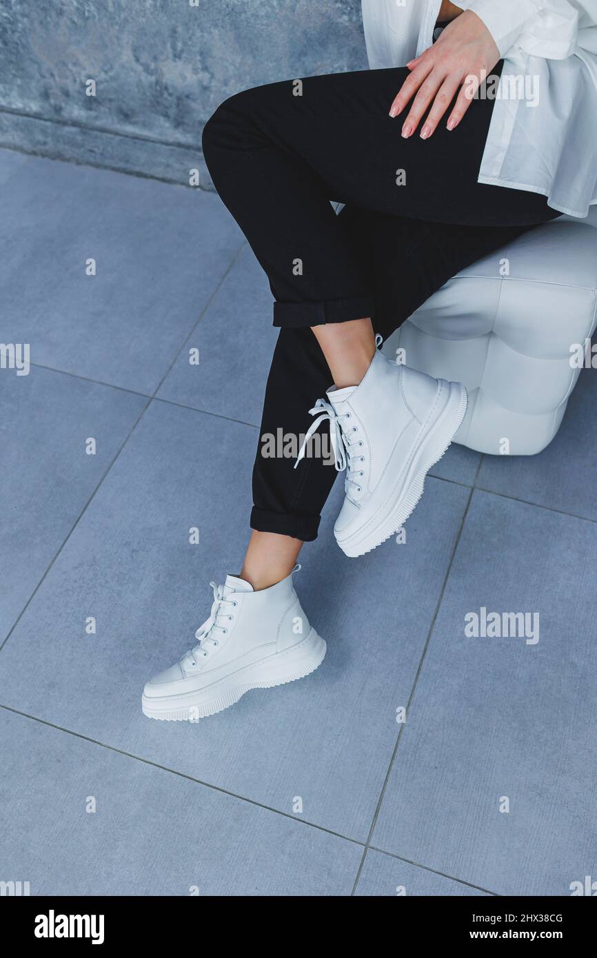 Women's legs in black trousers and white leather sneakers. Modern casual  style. New shoe collection Stock Photo - Alamy
