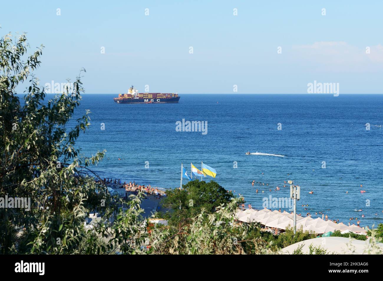 CHORNOMORSK, UKRAINE - AUGUST 9: The container ship transportation from Chornomorsk port and beach with Ukraininan flag on September 25, 2020 in Chorn Stock Photo