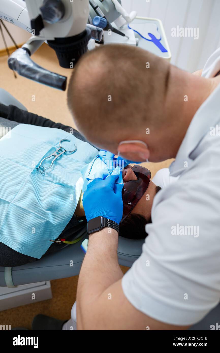 Patient with open mouth lying in the dentist's chair while the dentist