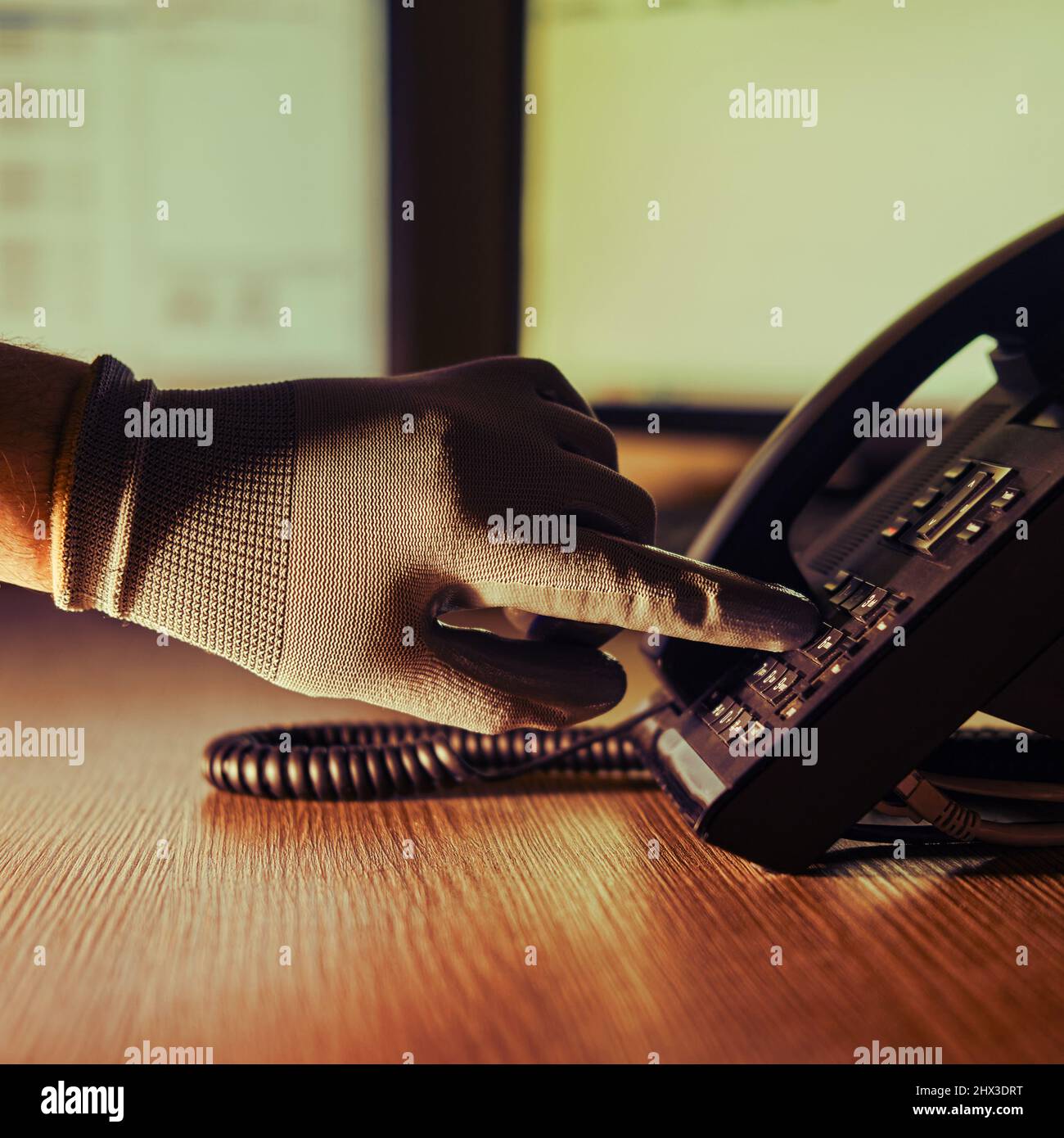 Telephone fraud and night theft by a criminal hacker on a phone conversation. A man hand in a black glove with a phone on a dark background Stock Photo