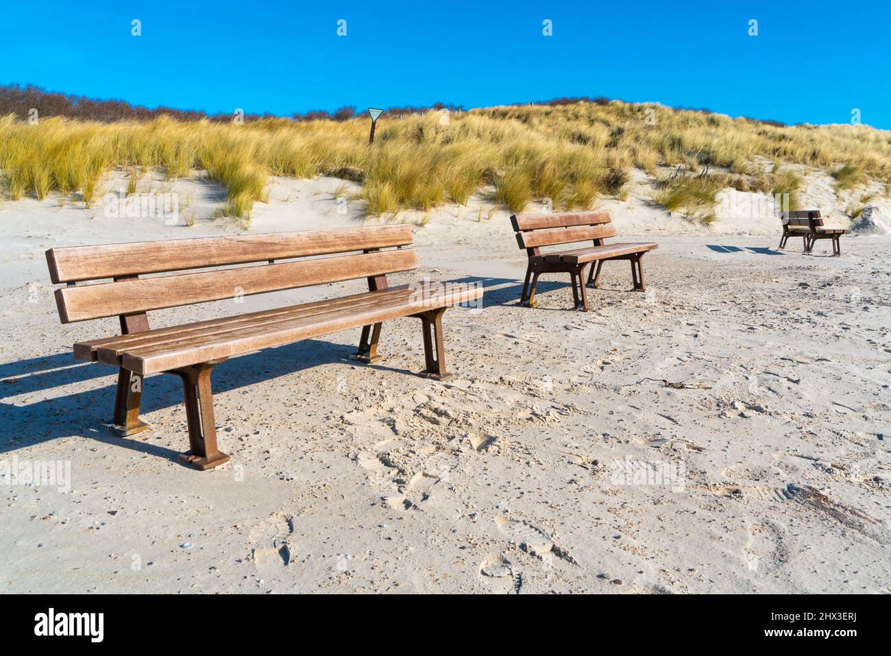 Three wooden benches on a sandy beach of the Dune island