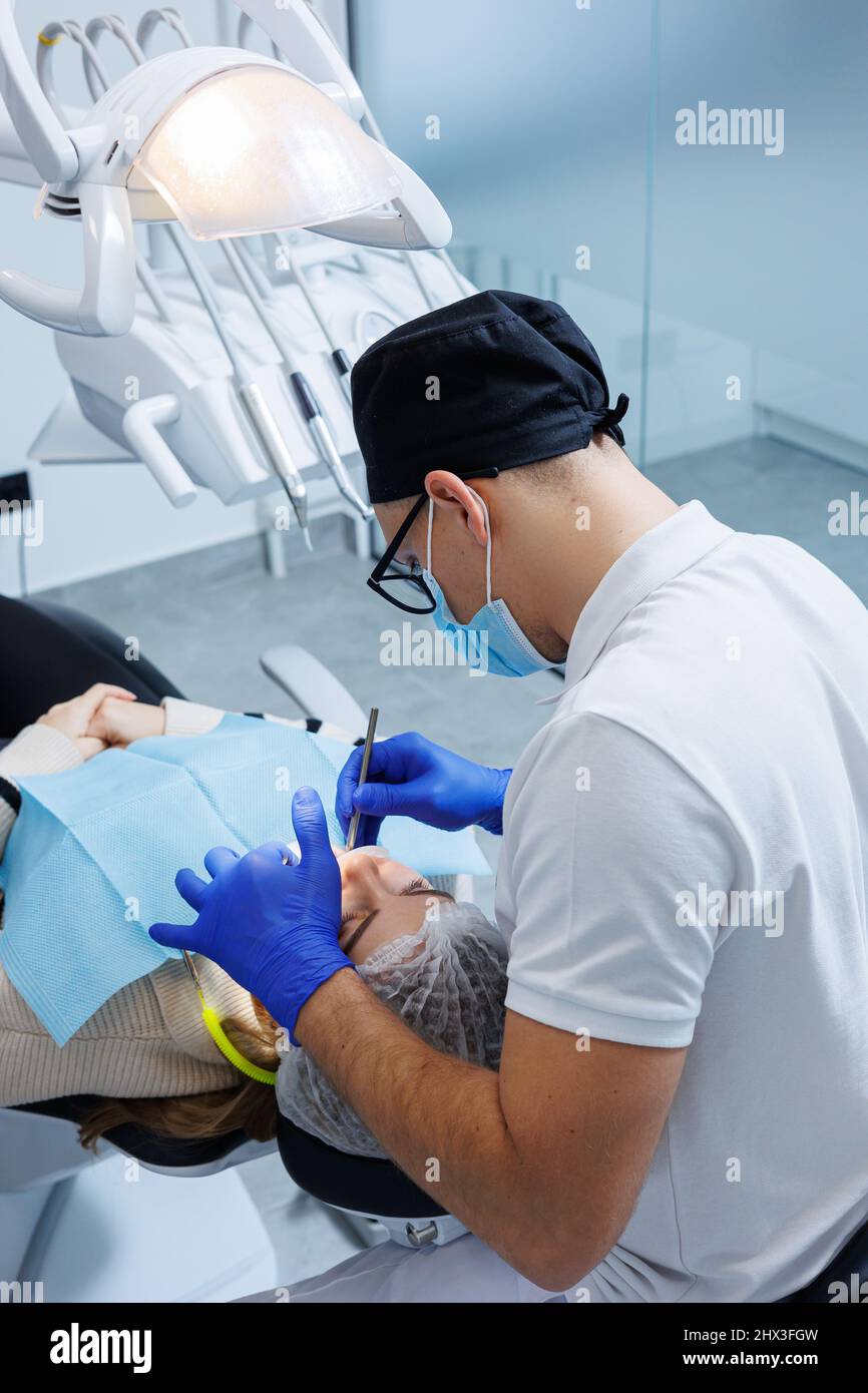 A professional dentist examines a patient's teeth with dental equipment