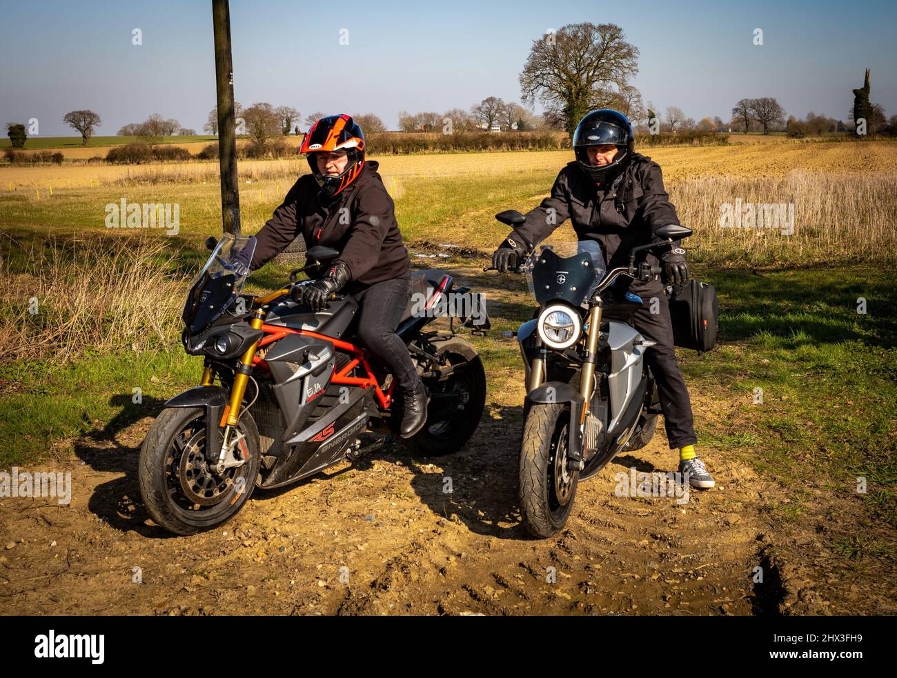 Two middle aged men motorcyclists sit on Energica EV electric motorcycles as they ready to move off. Stock Photo
