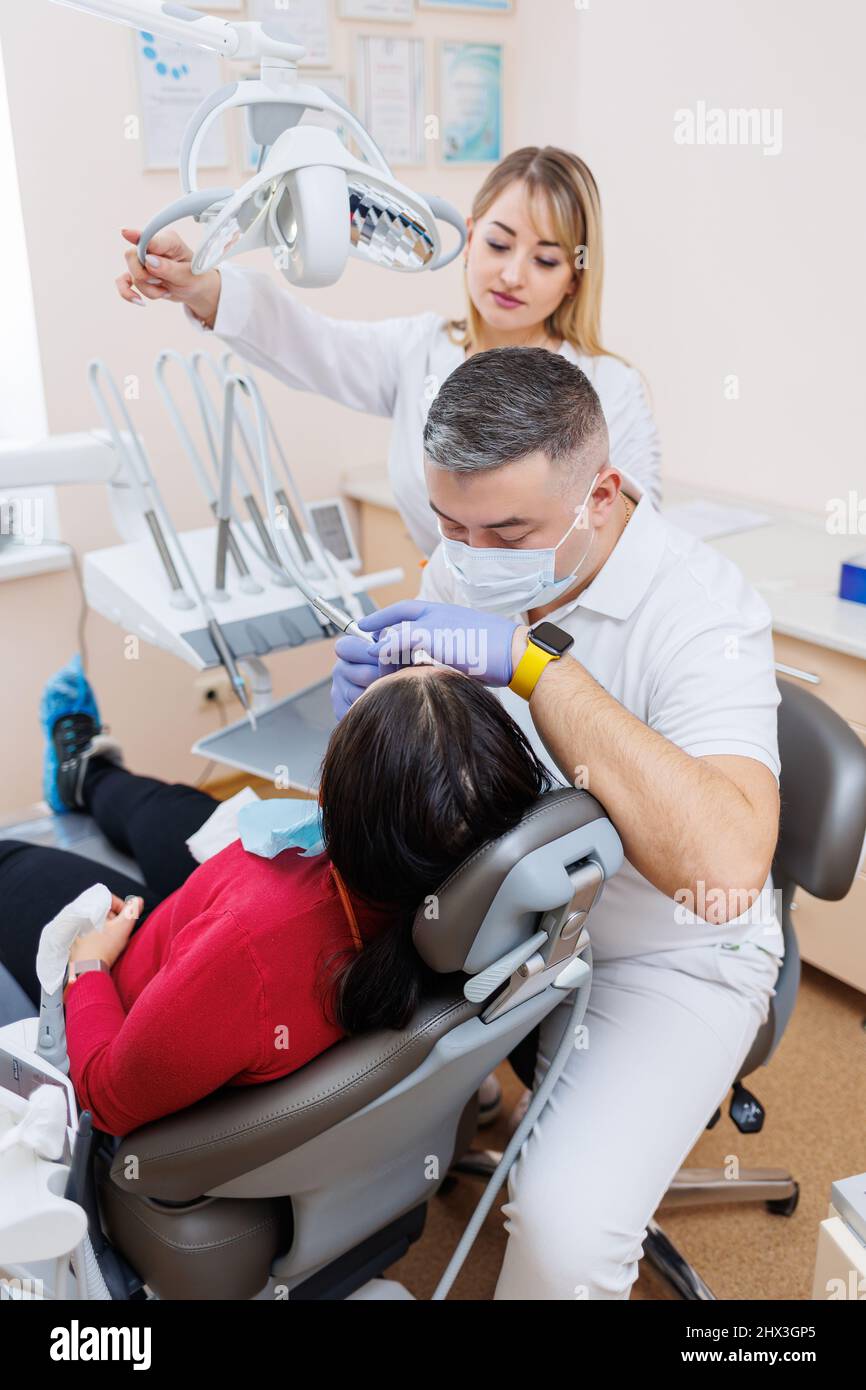 The dentist doctor looks at the patient's teeth and holds dental