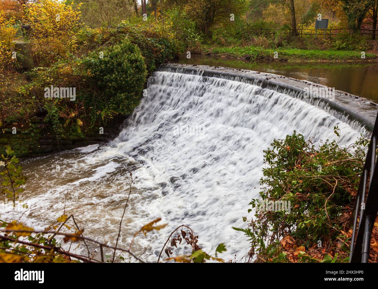 The historic curved weir on the River Bollin at Quarry Bank mill in Styal Cheshire with the mill pool above the weir Stock Photo