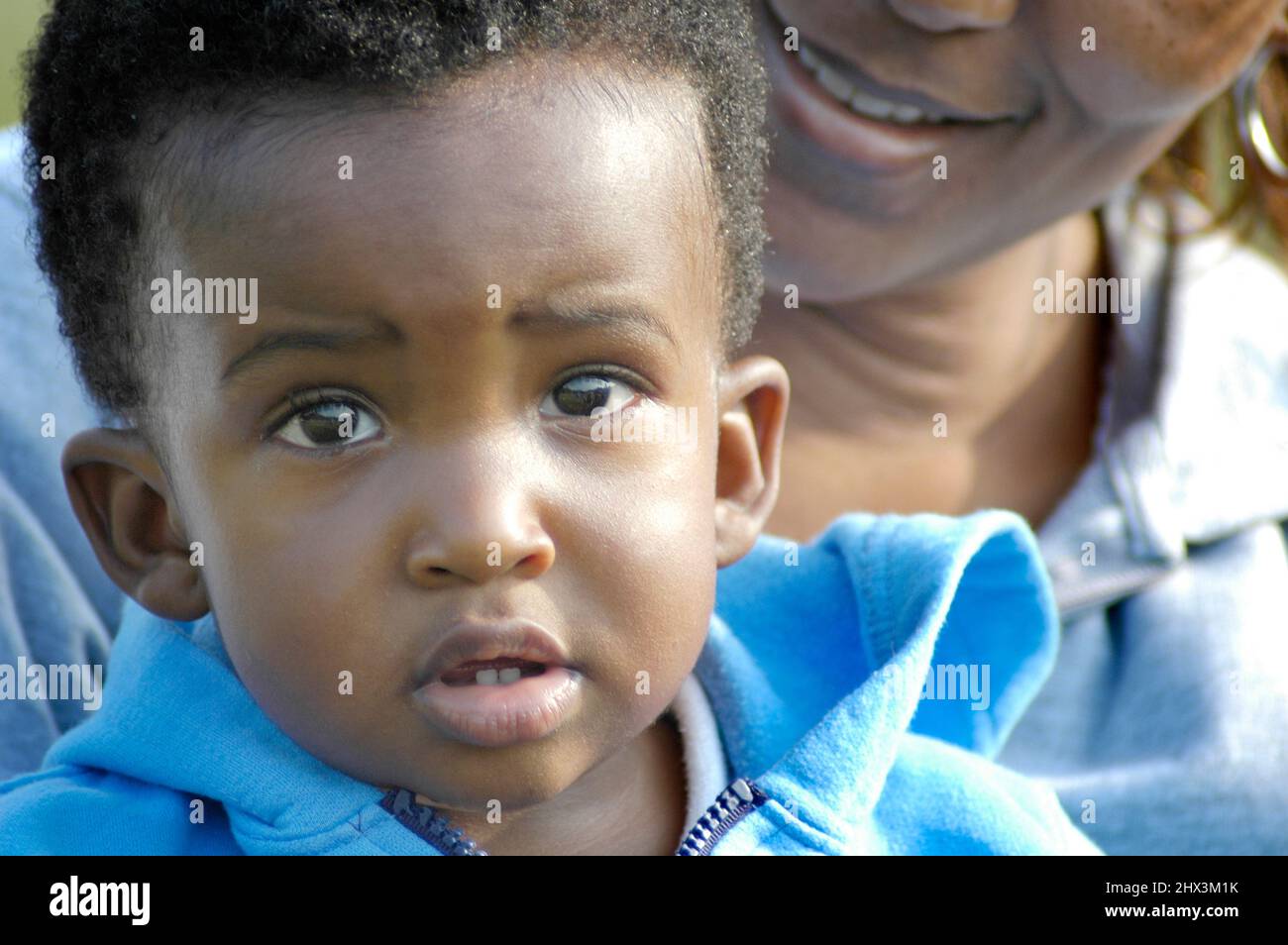 Baby Young toddler boy who is ethnic black looking full face at the camera  being held by his mom Stock Photo - Alamy