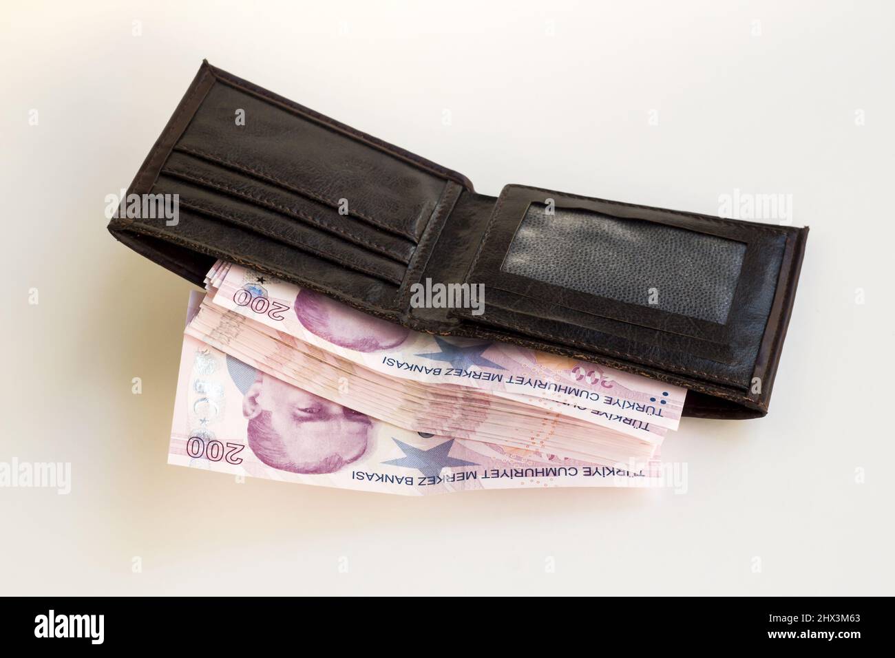 Brown leather men's wallet, fully loaded with Turkish two-hundred banknotes, on a white surface Stock Photo
