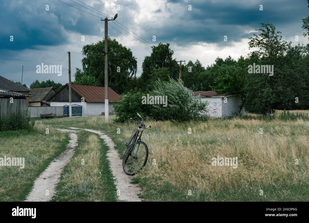 Rusty old bicycle waiting for the rider on the roadside in village of central Ukraine Stock Photo