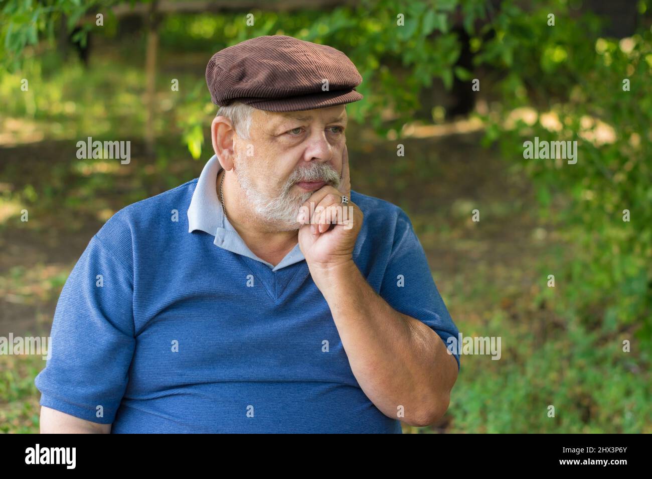 Nice outdoor portrait of Caucasian bearded senior man under tree shadow Stock Photo