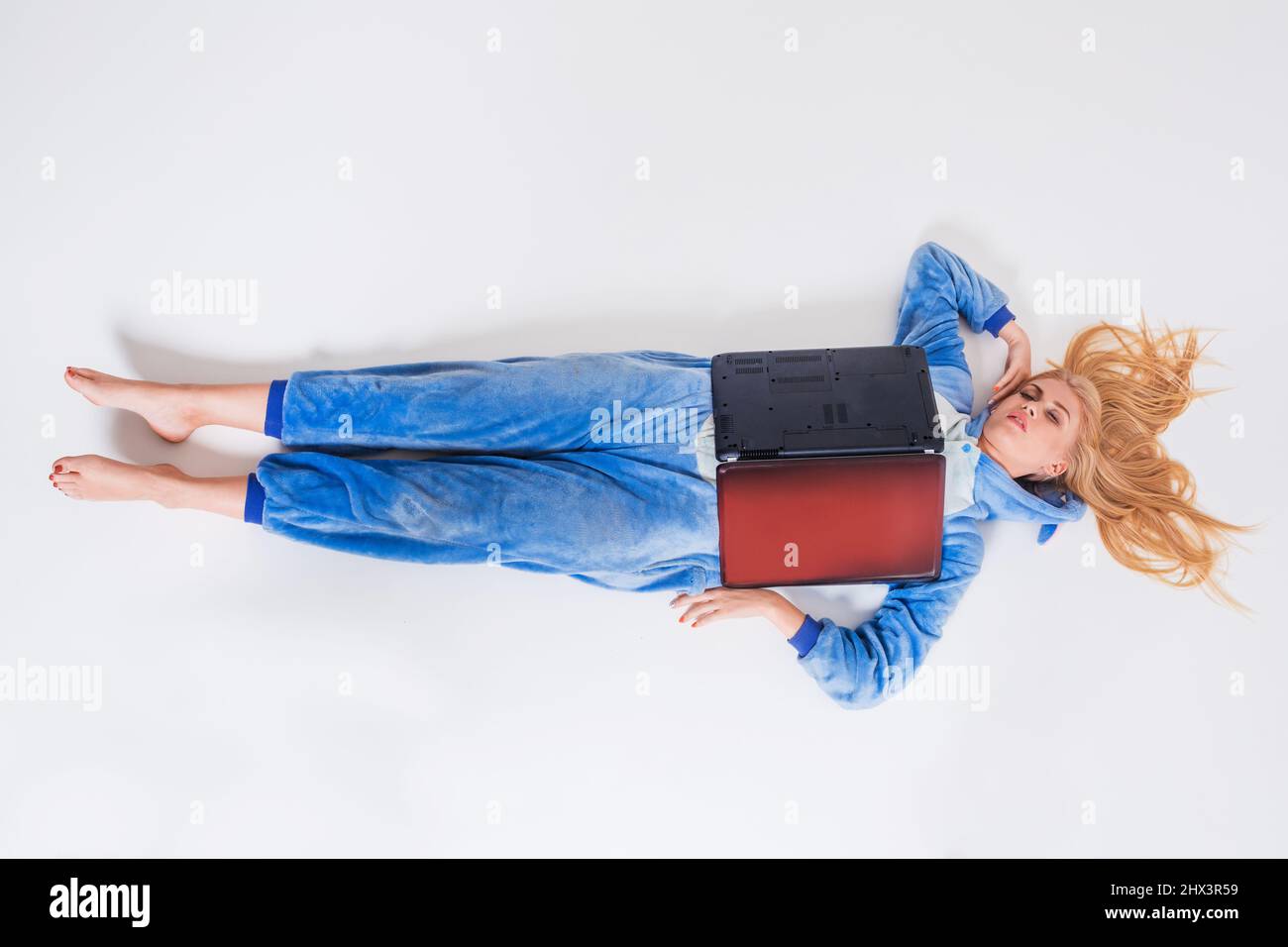 young woman lying on the floor in his pajamas with a laptop Stock Photo