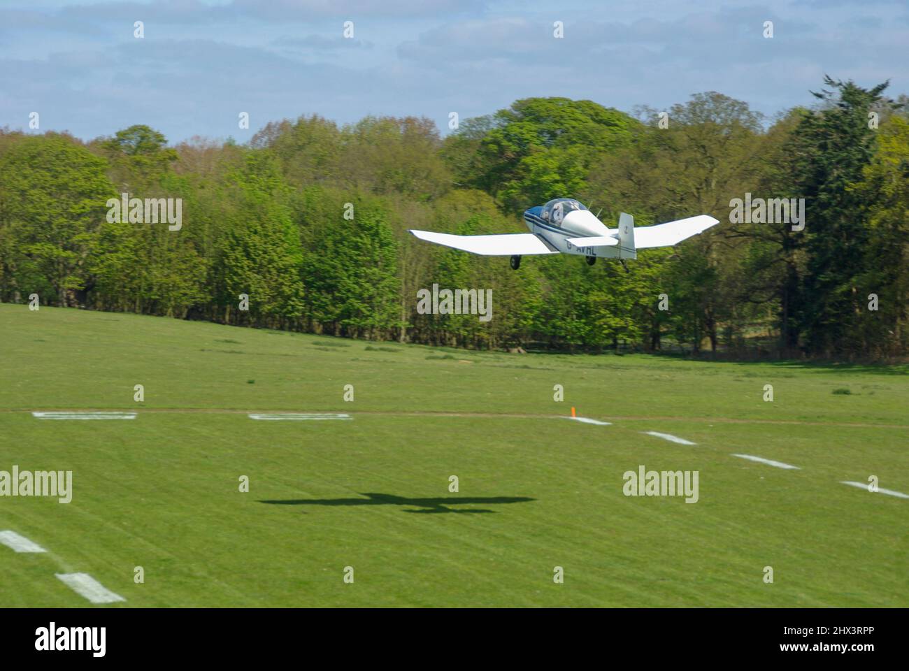 Jodel DR-105A Ambassadeur plane G-AVHL taking off from Henham Park countryside grass strip. Tree lined Suffolk grass runway on sunny day Stock Photo