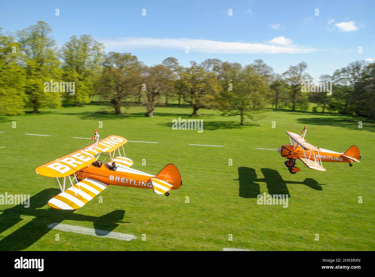 Aerosuperbatics Boeing Stearman planes taking off from Henham Park countryside grass strip. Tree lined Suffolk grass runway on sunny day. English park Stock Photo