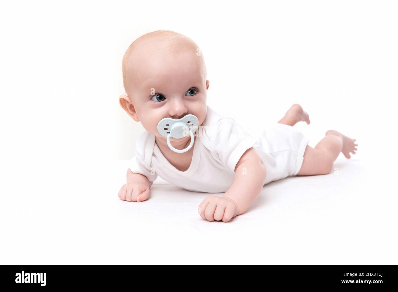 surprised charming baby with a pacifier in his mouth on a white