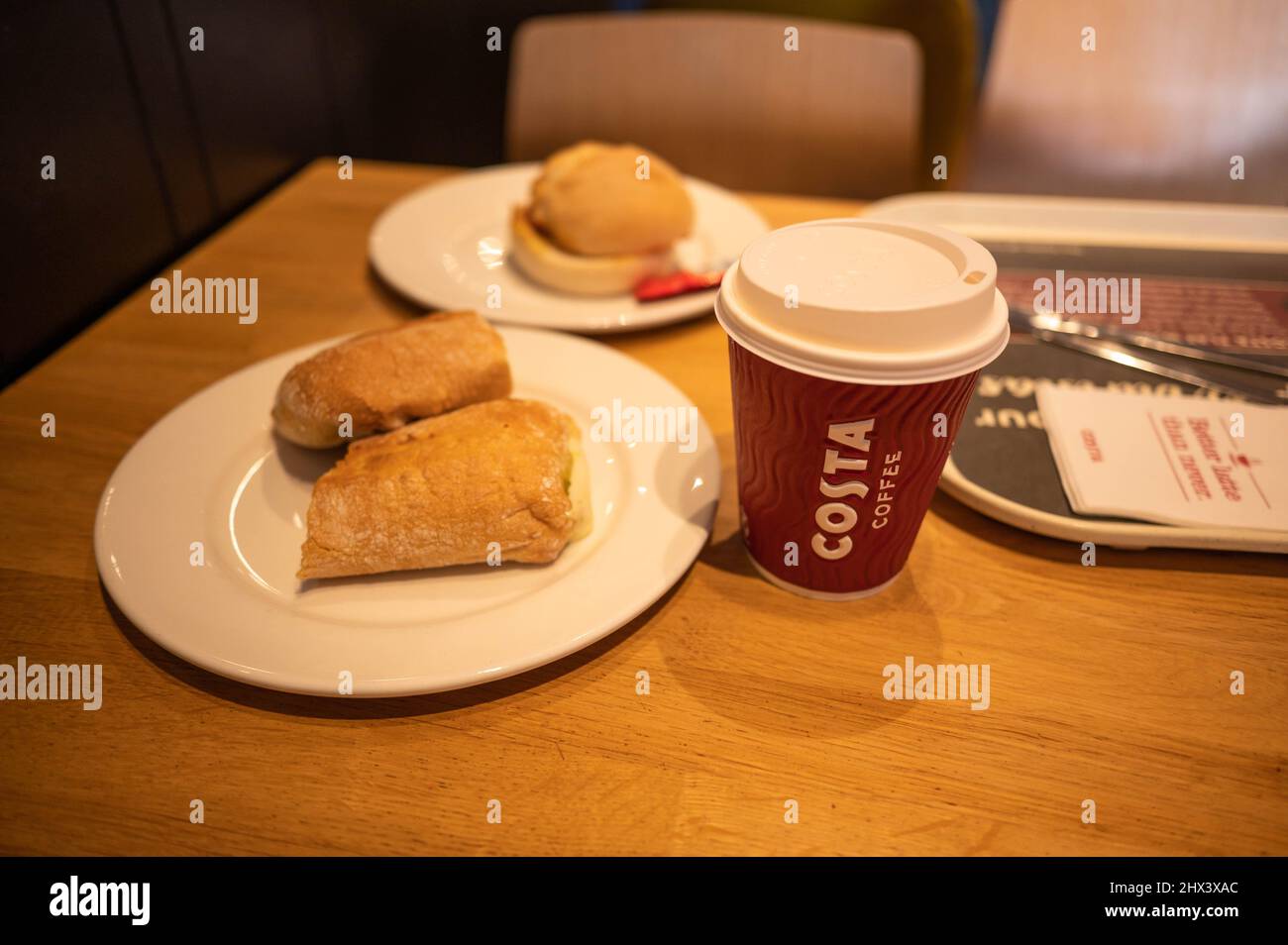 Costa indoor table with costa cup of coffe, bacon roll ,costa panini