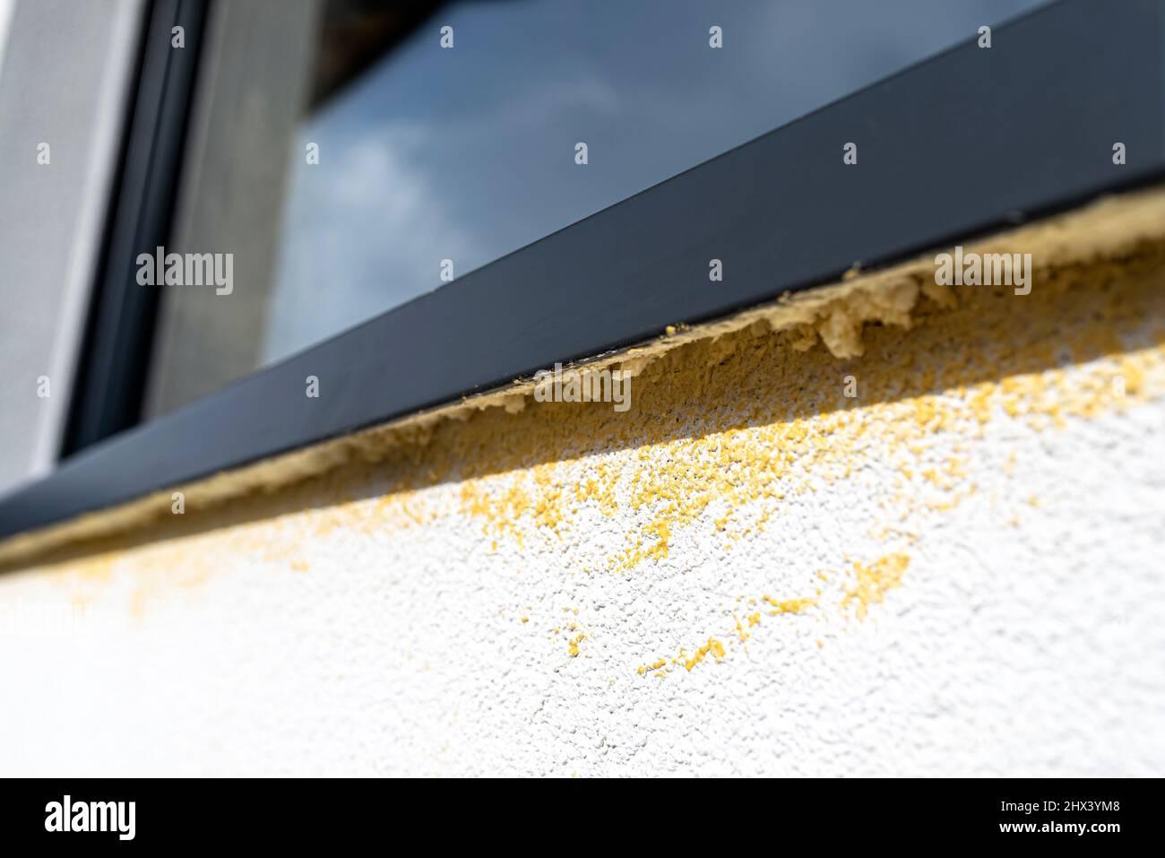 Yellow mounting foam filled under the window sill, white plaster is stained by sloppy work. Stock Photo