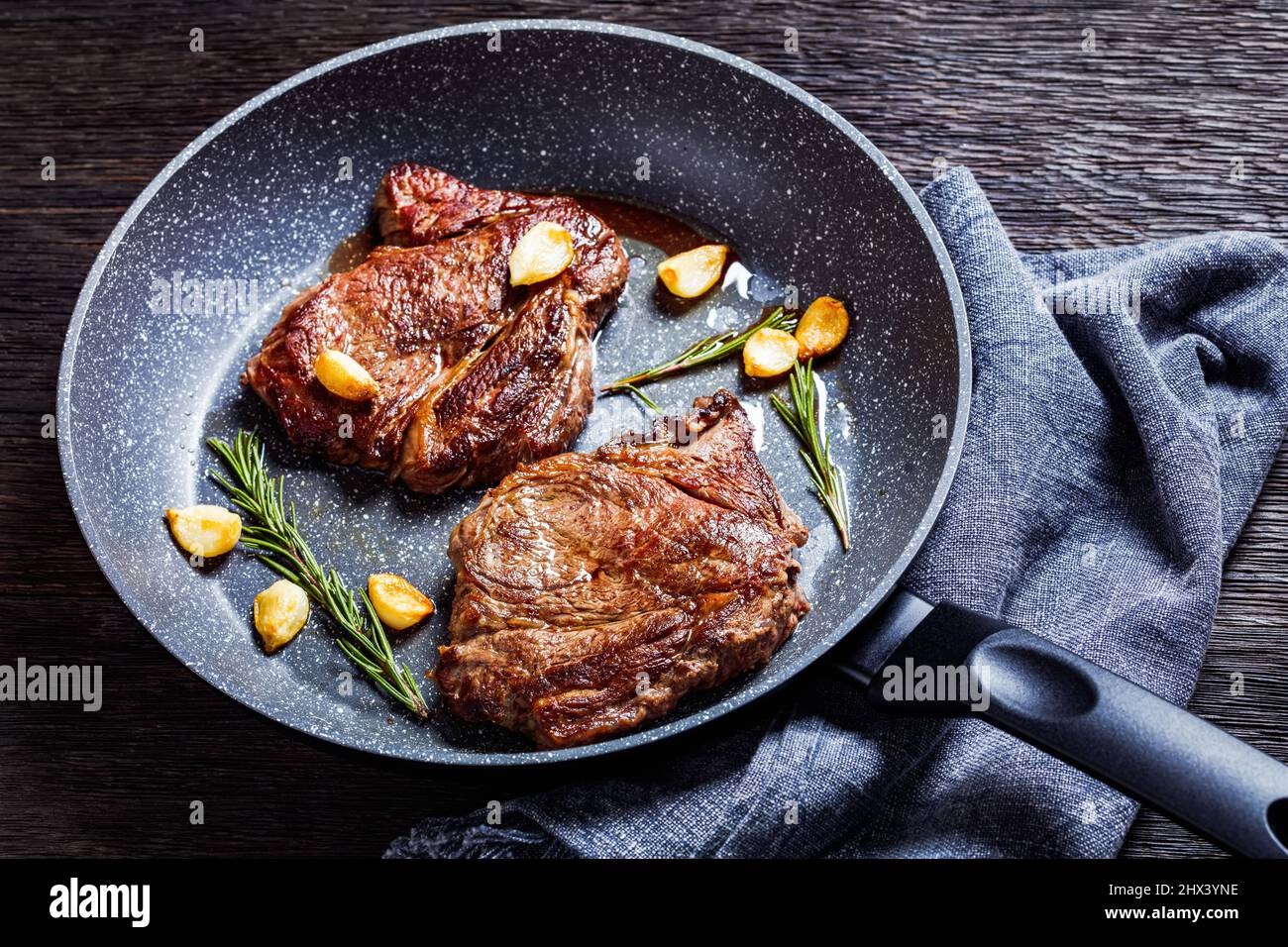 fried juicy chuck eye beef steaks with fried garlic cloves and rosemary