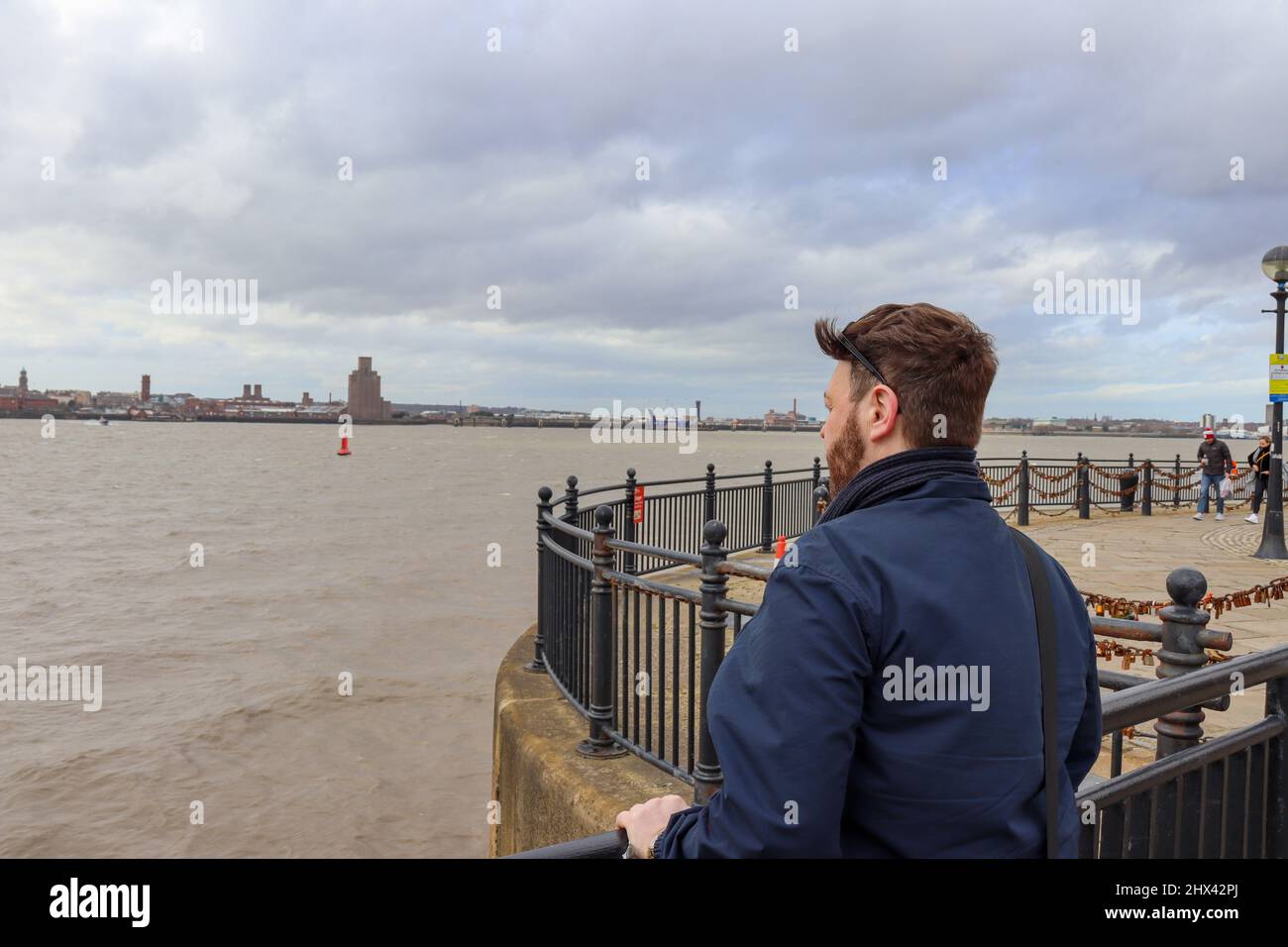 Young man with fabulous hair looking out to sea, looking towards Wirral from Liverpool Stock Photo