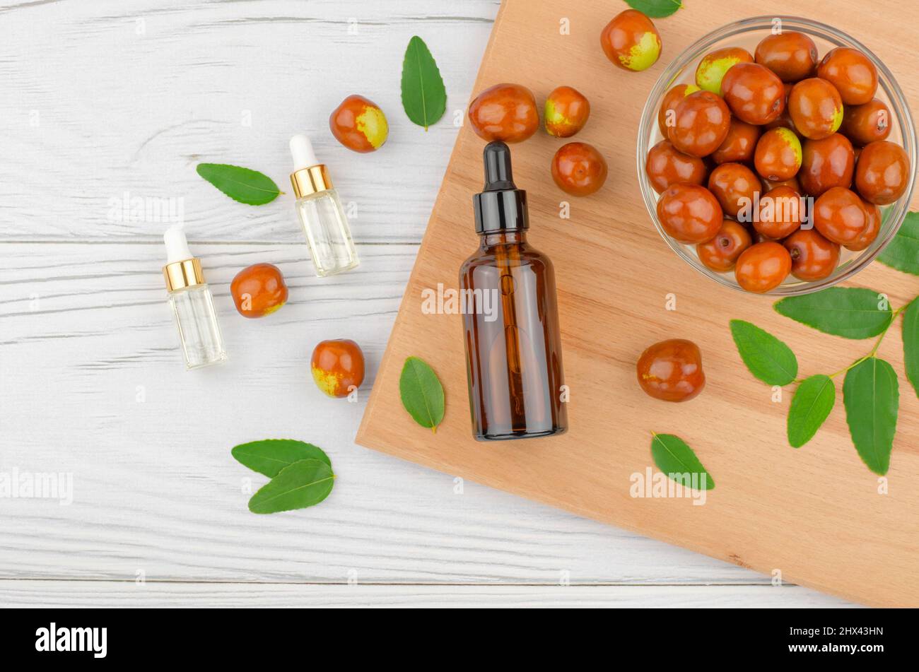Jojoba oil in a bottle with a dropper and fresh jojoba fruits on a wooden table Stock Photo