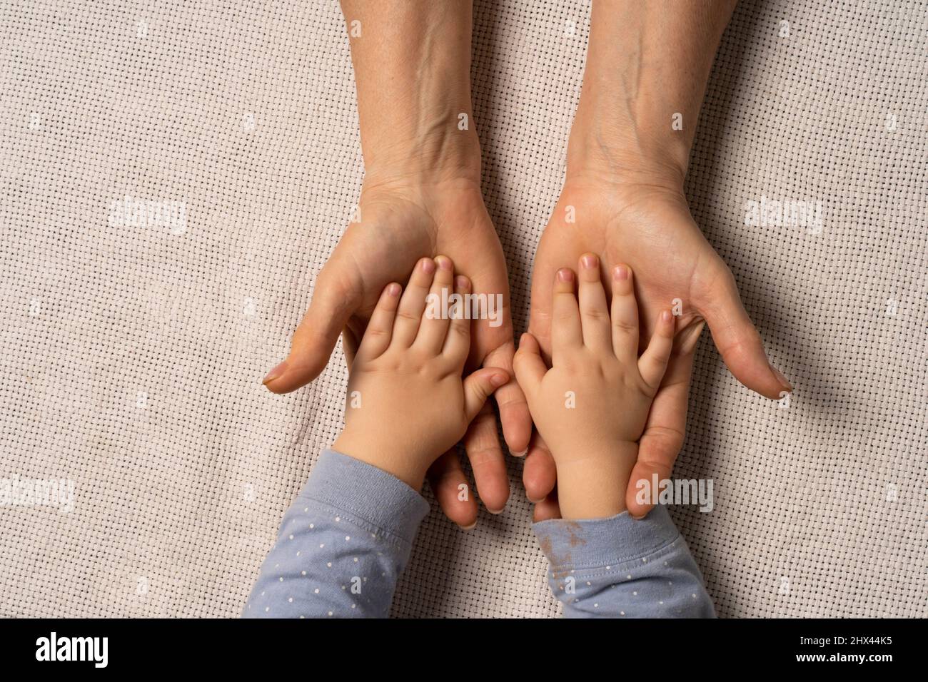 Grandma's hands are holding baby's hands. Concept taking care of the baby , soft skin, great-grandmother and great-grandson. Stock Photo
