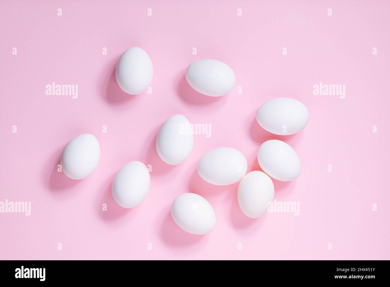 White easter eggs on pink background. Top view. Different shapes like easter bunny made from white eggs. Happy Easter simple concept Stock Photo