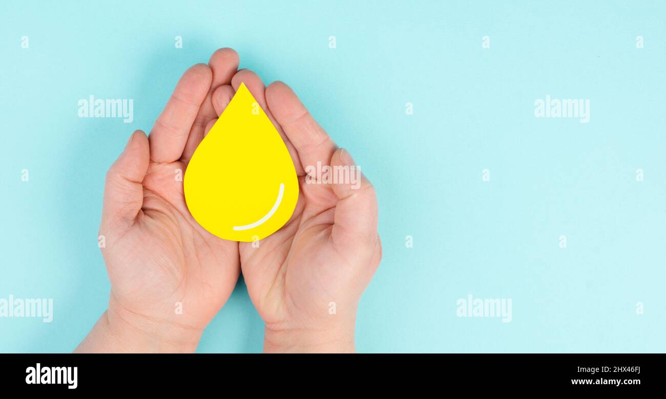 Holding a yellow drop, symbol for gas, petrol, diesel and oil, price increase caused by boycott, inflation, renewable energy Stock Photo