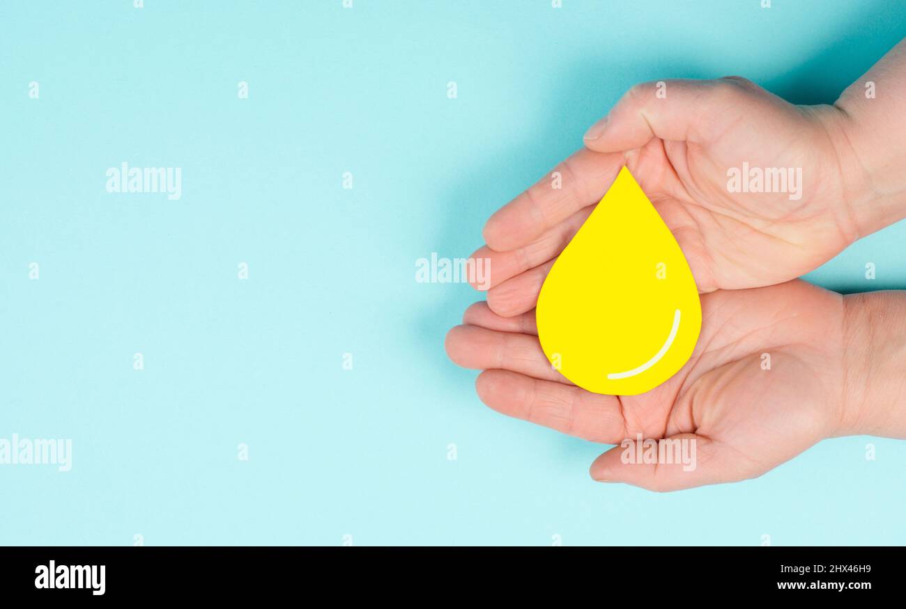 Holding a yellow drop, symbol for gas, petrol, diesel and oil, price increase caused by boycott, inflation, renewable energy Stock Photo