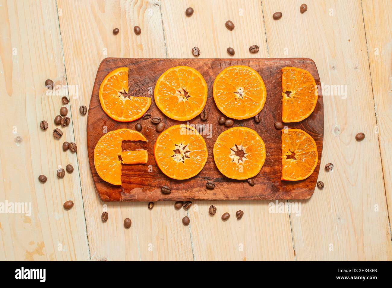 good food, written with orange slices font on a wood chopper. Stock Photo