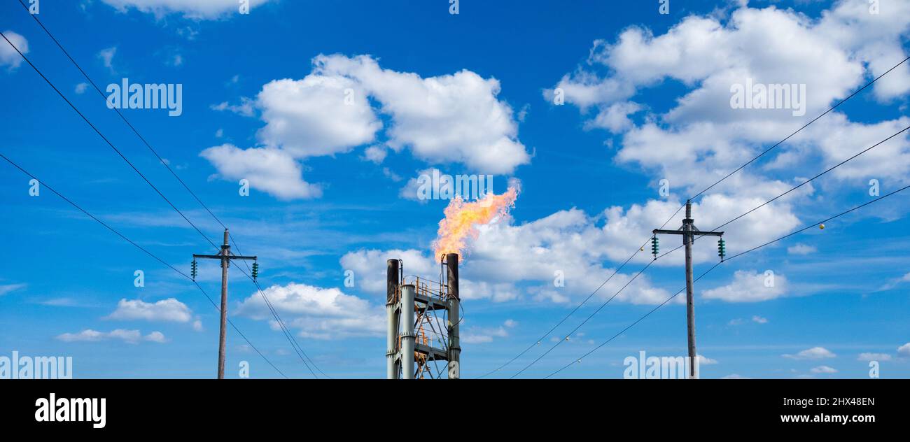 Electricity cables and industrial gas flare chimney rising energy