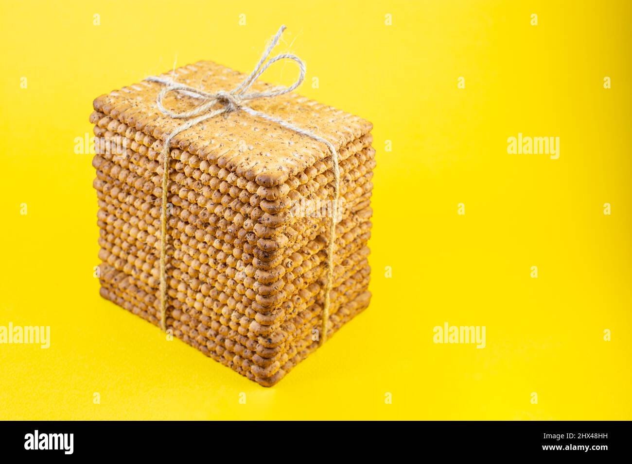 staked biscuits present, tied with jute rope bow and isolated on yellow Stock Photo