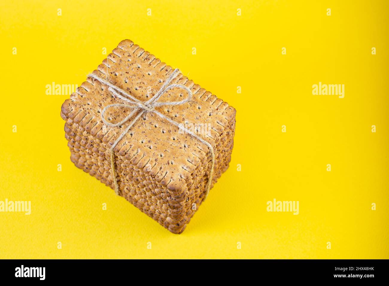 Rye biscuits stacked and tied with a jute rope bow on yellow background Stock Photo