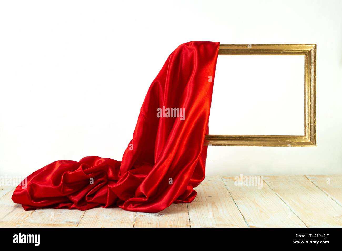 red satin cloth unveiling a golden frame. Levitating frame, mockup for presentation. Stock Photo