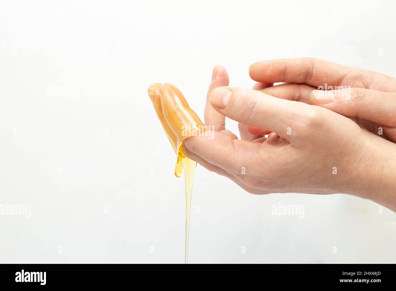 Woman's hands applying dripping honey on dried skin Stock Photo