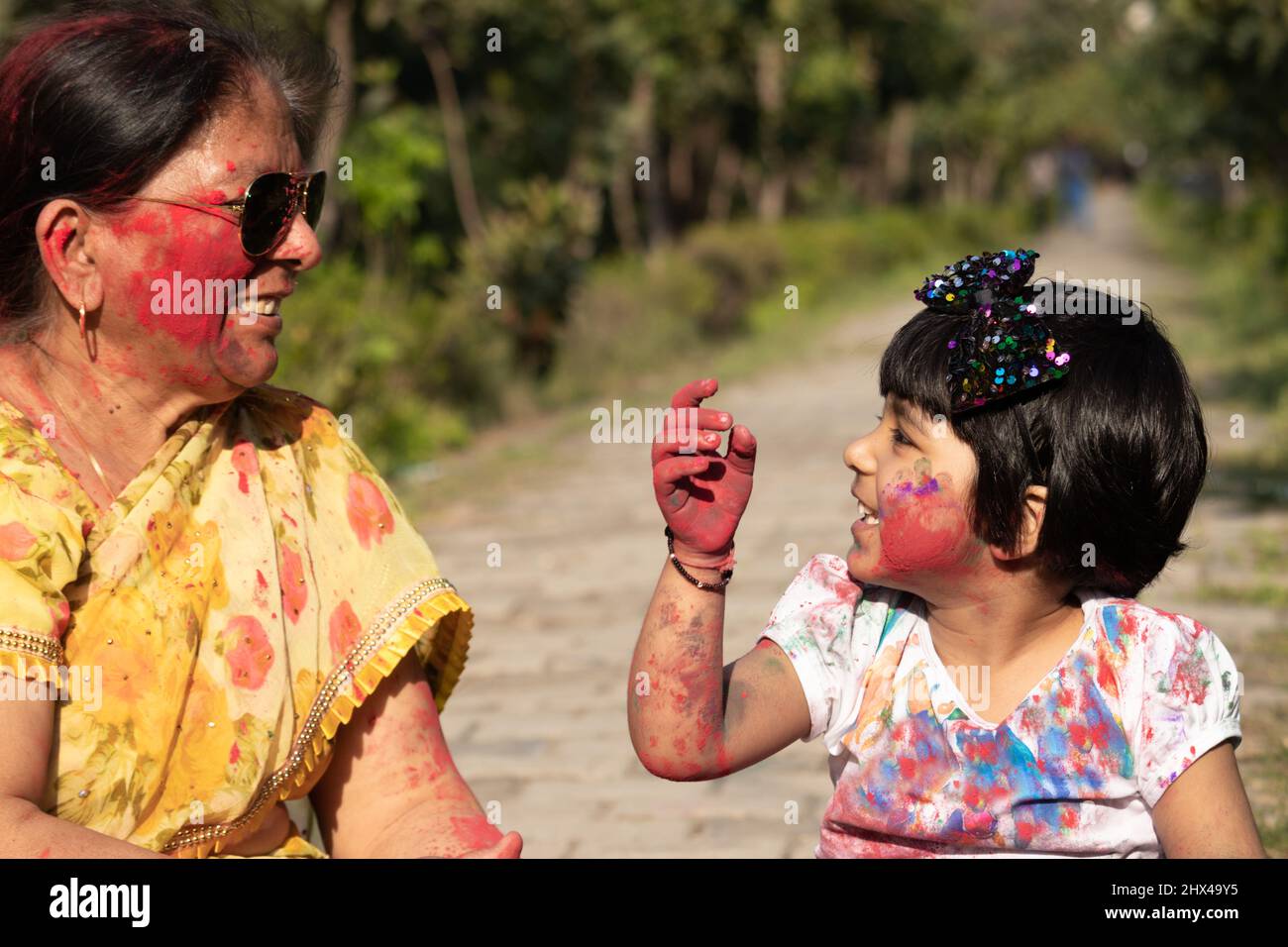 Elderly Indian Lady And Kid Enjoying Holi With Gulal Or Abir Rang Abeer. Festive, Family, Fun, Celebration, Enjoyment, Togetherness, Multi Generation, Stock Photo